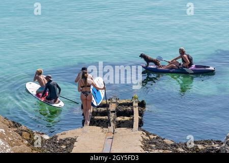 Urlauber auf Kajaks und Stand Up Paddleboards in einer ruhigen Newquay Bay in Cornwall. Stockfoto