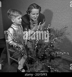 Ein kleiner Junge schreibt-Wunschzettel an den Weihnachtsmann mit der Schreibmaschine und gibt ihn seiner Mutter zur Weiterleitung, Deutschland 1930er Jahre. Ein kleiner Junge mit der Eingabe seiner Liste der Wünsche und gibt ihm seine Mutter zur Weiterleitung an Santa, Deutschland 1930. Stockfoto