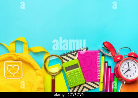 Rahmen aus Schule und Büro Zubehör Büroklammern, Scheren, Stifte, Filzstifte, Spitzer, Rechner, Hefter isoliert auf blauem Hintergrund Flat Lay Stockfoto