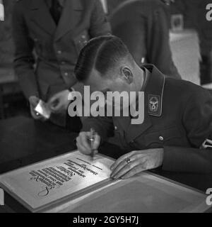 Reichsleiter leistet eine Unterschrift, Deutschland 1930er Jahre. Reichsleiter unterzeichnet ein Dokument, Deutschland 1930er Jahre. Stockfoto