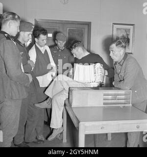 Original-Bildunterschrfit: Eine Gruppe im Treppenhaus des Schiffs "Wilhelm Gustloff" hört einem Kameraden beim Ziehharmonikaspiel zu, Deutschland 1940er Jahre. Eine Gruppe von Soldaten listenening zu einem Kameraden seiner Ziehharmonika spielen auf das Schiff "Wilhelm Gustloff", Deutschland 1940. Stockfoto