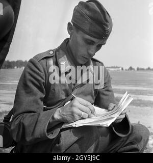 Original-Bildunterschrift: Soldat der Nachrichtentruppe bei der Aufnahme einer Meldung / Diktat Waden abhörenden Kameraden, Deutschland 1940er Jahre. Soldat des Signal Corps Aufnahme eines diktiert Hinweis von seinem Kameraden, Deutschland 1940. Stockfoto