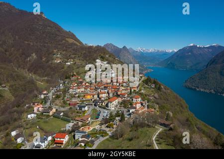 Luftaufnahme des Luganer Sees und des Dorfes Monte Brè im Kanton Tessin in der Südschweiz. Sonniger Tag Stockfoto