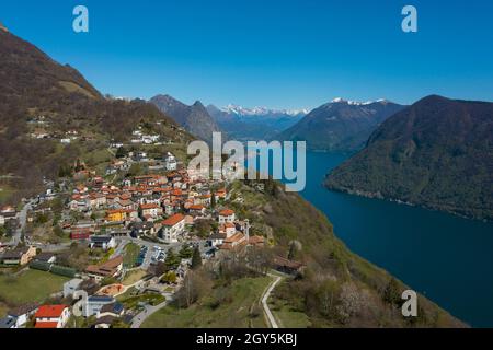 Luftaufnahme des Luganer Sees und des Dorfes Monte Brè im Kanton Tessin in der Südschweiz. Sonniger Tag Stockfoto