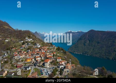 Luftaufnahme des Luganer Sees und des Dorfes Monte Brè im Kanton Tessin in der Südschweiz. Sonniger Tag Stockfoto