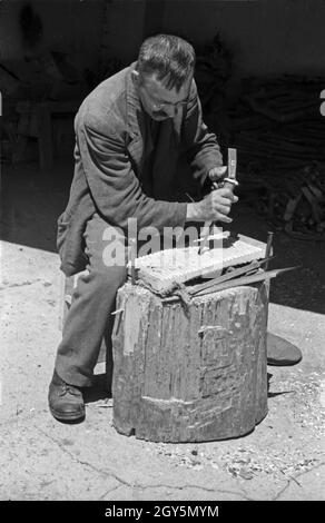 Ein Holzbildhauer beim Schnitzen, Deutschland 1940er jahre. Ein Holzschnitzer-Autowerk, Deutschland 1940er Jahre. Stockfoto