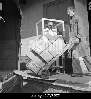 Der Lehrling beladt einen KW mit Maccaronikästen, Deutschland 1940er Jahre. Lehrling, der einen Lastwagen mit Makkaroni-Nudeln beladen hat, Deutschland 1940er Jahre. Stockfoto