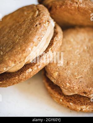 Hausgemachtes Peanut-Butterkekse-Dessert mit Nusscreme-Sandwich auf weißem Teller, selektiver Fokus, Nahaufnahme. Handwerkliches Dessertkonzept Stockfoto