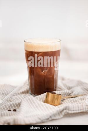 Gekühltes Americano- oder Espresso Tonic-Kaffee kaltes Cocktailgetränk in hohem Glas auf weißem Hintergrund, Nahaufnahme, selektiver Fokus. Idyllisches Getränk für eine Pause Stockfoto