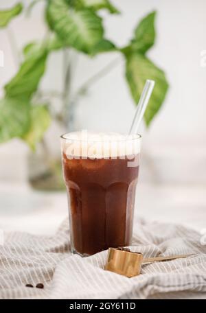 Gekühltes Americano- oder Espresso Tonic-Kaffee kaltes Cocktailgetränk in hohem Glas mit Stroh auf weißem Hintergrund, Nahaufnahme, selektiver Fokus. Idyllisch, drin Stockfoto