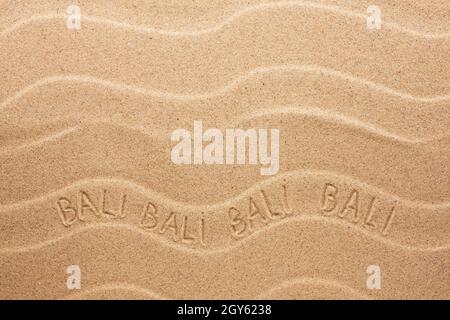 Bali-Inschrift auf dem welligen Sand als Hintergrund Stockfoto