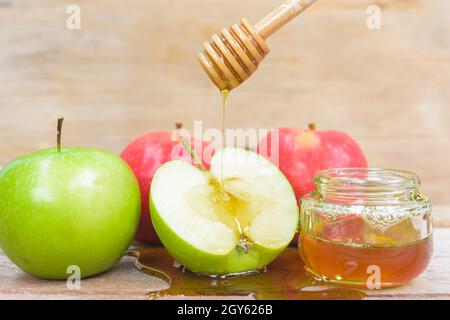 Jüdische Feiertag, Apple Rosch Haschanah, das Foto haben Honig im Glas und Tropfen Honig auf grüne Äpfel auf hölzernen Hintergrund Stockfoto