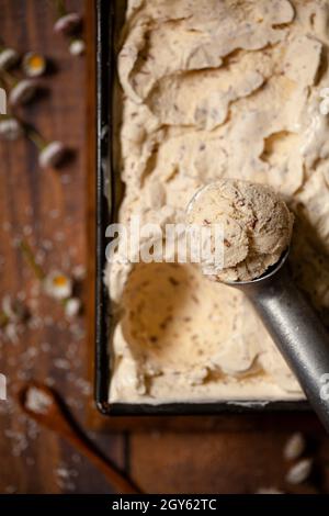 Eine Wanne mit Schokolade und Kokoseis mit einer Kugel am Rand der Wanne Stockfoto