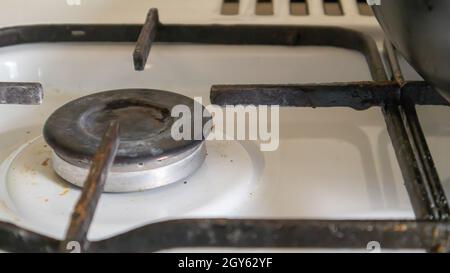 Schmutziger Gasherd in der Küche zum Kochen mit Pflanzenölflecken und verbrannten Speisereste auf der Oberfläche, Nahaufnahme. Selektiver Fokus. Mit Fett überzogene g Stockfoto