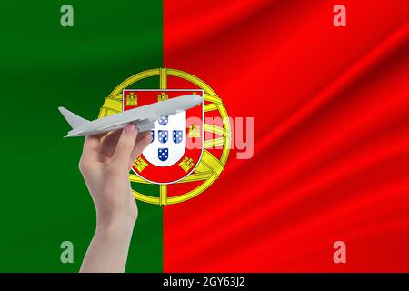 Flugzeug in der Hand mit der Nationalflagge Portugals. Reise nach Portugal. Stockfoto