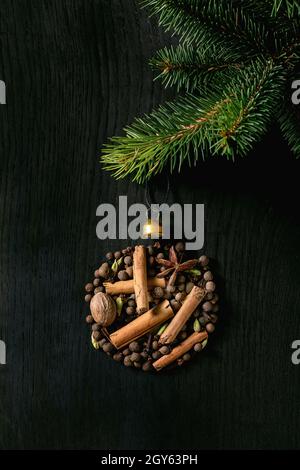 Aromatische Gewürzkollektion, Glühwein-Zutaten als Weihnachtskugel mit Tannenbaum. Piment, Zimtstangen, Kardamom, Nelke, Muskat über bla Stockfoto