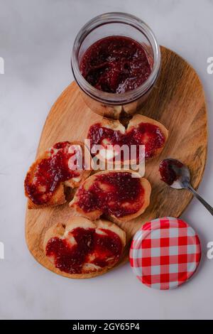 Scheiben geröstetes Brot mit Butter und Marmelade auf Holzbrett und hellem Hintergrund. Komposition von selbstgemachtem Stau mit Kopierplatz. Stockfoto