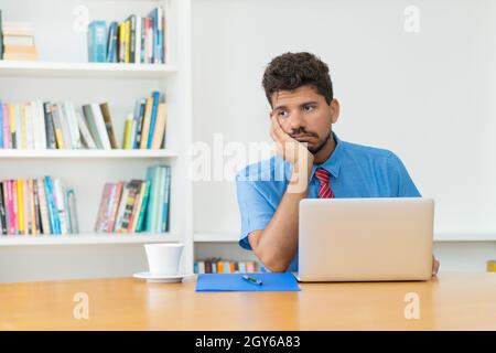 Trauriger und frustrierter hispanischer Geschäftsmann mit Depressionen im Büro Stockfoto