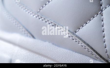 Nahaufnahme aus Synthetikgewebe mit weißen Diamantnähten und weißer Gummisohle. Sportschuhe. Gesteppte Qualität in Weiß oder hellen Farben, Textur Stockfoto