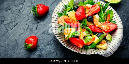 Diätsalat mit Garnelen, Erdbeeren, Avocado und Grün. Gesunder Salat aus stilvollem Metall Platte Stockfoto