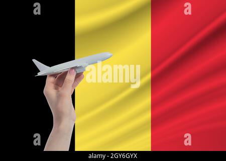 Flugzeug in der Hand mit der Nationalflagge Belgiens. Reise nach Belgien. Stockfoto