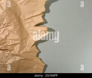 Mintbraunes Stück Papier mit abgerissenen Kanten und Schatten auf grauem Hintergrund. Abstrakter kreativer Hintergrund für Designer, Kopierbereich Stockfoto