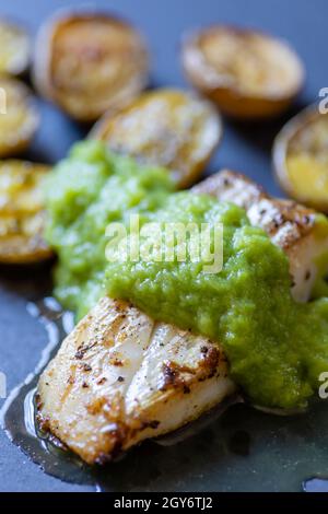 Kabeljaufisch mit grüner Spargelsauce und gebratenen Kartoffeln Stockfoto