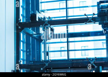 Glasaufzug, Geschäftsmann, der einen modernen Glasaufzug zu den oberen Etagen, zum Hochhaus, zum Büro und Einkaufszentrum und zum Hotel nimmt, Transport. Stockfoto