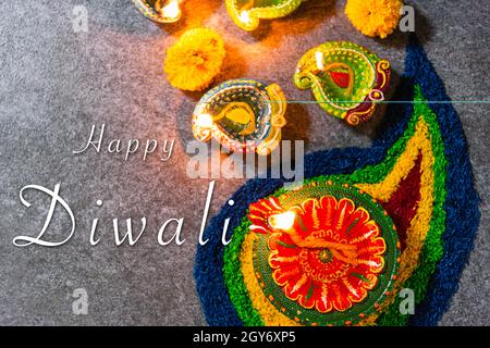 Nahaufnahme Ton beleuchtet ein Feuer bereits auf Diya oder Öllampe mit Blumen auf Beton Hintergrund, Dekoration des Hinduismus rangoli, Happy Celebration tief Stockfoto