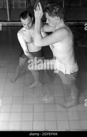 Ein Patient bei der Unterwasserbehandlung mit einem Bademeister, Deutschland 1930er Jahre. Ein Patient in einem Heilbad, Deutschland 1930. Stockfoto