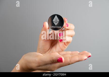 Frau zeigt ethereum-Münze in ihren Händen, beschnittene Ansicht. Finanz- und Technologiekonzept. Stockfoto