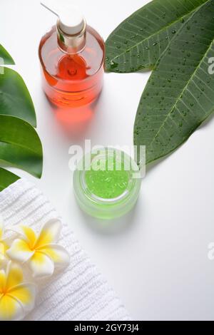 Kosmetikflaschen mit grünen Kräuterblättern und weißen Blumen, Blank-Etikett für Branding-Mock-up, Naturkosmetik, Spa, Wellness, Massage Stockfoto