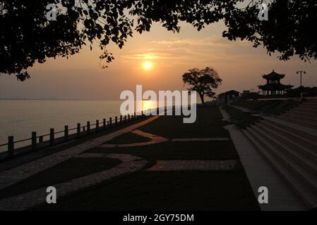 Der Park wurde als Aussichtsplatz für die Gezeitenströmung an der Mündung des Qiantang River genutzt. Nördliches Ufer des Qiantang Flusses bei Hangzhou bei Sonnenuntergang. Stockfoto