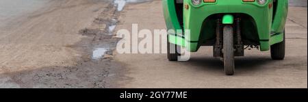 Grün und gelb umweltfreundliche elektronische Tuk Tuk Fahrzeug Auto Rikscha in Luang Prabang Laos Asien. Stockfoto