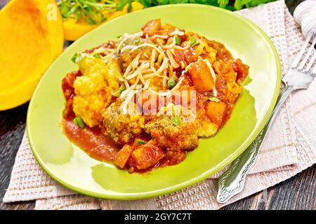 Maisbrei mit Fleischbällchen, Tomatensoße, Knoblauch und Kürbis, bestreut mit Käse und Petersilie auf einem Teller auf einem Handtuch vor dem Hintergrund von dar Stockfoto