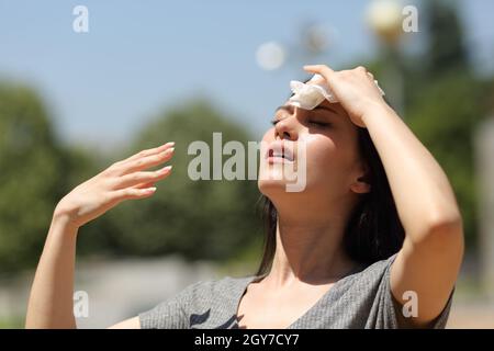 Gestresste asiatische Frau trocknet Schweiß mit einem Tuch an einem warmen Sommertag Stockfoto