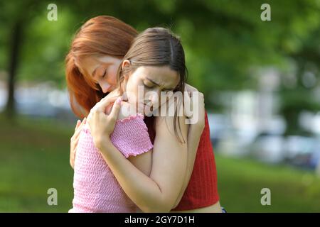 Traurige Mädchen, die sich versöhnten, nachdem sie sich in einem Park umarmten Stockfoto