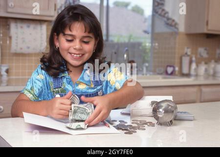 Austin-Texas USA, Juni 1998: Die 8-jährige Panamanisch-Amerikanerin zählt Geld von ihrer Sparkasse, während sie eine Einzahlung auf ihr Bankkonto vorbereitet. ©Bob Daemmrich Stockfoto