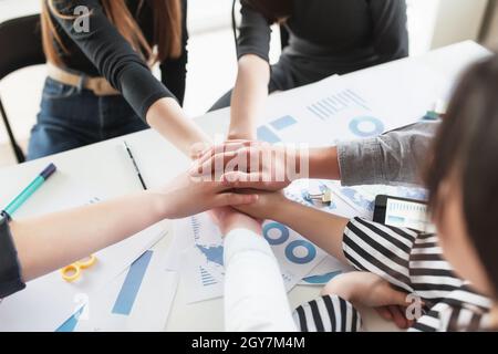 Eine Gruppe von Menschen, die Handschlag und Kreuzhände machen. Freundschaft, Übereinkunft, Kooperationskonzept mit jungen Teenagern, die sich die Hände kreuzen Stockfoto