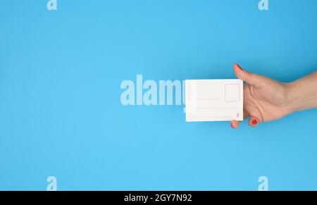 Weibliche Hand hält Papier unbeschriftete Plakette Einsatz auf blauem Hintergrund, Copy Space Stockfoto