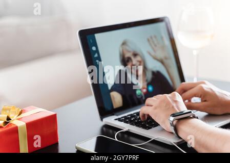 Generationsübergreifende Familie feiert Weihnachten mit Videoanruf - Senior Woman chatten und treffen sich auf einem Laptop - Fokus auf die linke Hand Stockfoto