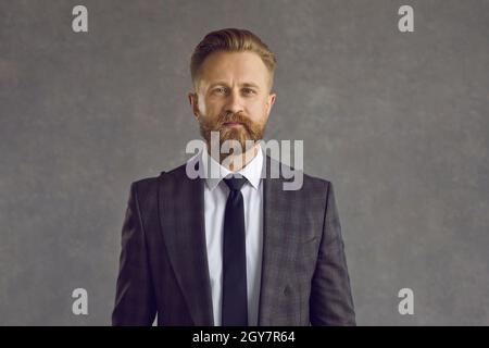 Nahaufnahme eines ernsthaften kaukasischen Geschäftsmannes vor grauem Hintergrund. Stockfoto