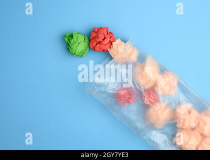 Transparente Plastiktüte mit zerknittertem Papier auf blauem Hintergrund, Draufsicht Stockfoto