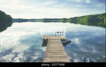 Hölzerner Pier am ruhigen Lipie-See, farblich getöntes Bild, Polen. Stockfoto