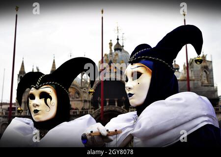 VENEDIG, ITALIEN - 09. Feb 2016: Zwei Joker verkleidete Maskeraden beim Karneval von Venedig mit der Markusbasilika im Hintergrund. Passende Kostüme Co Stockfoto