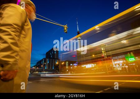 Berlin, Deutschland. Oktober 2021. Ein Mann wartet mit Mundnasenschutz an einer Ampel, während ein BVG-Bus an ihm vorbeifährt. (Aufgenommen mit Langzeitbelichtung) Credit: Fernando Gutierrez-Juarez/dpa-Zentralbild/dpa/Alamy Live News Stockfoto