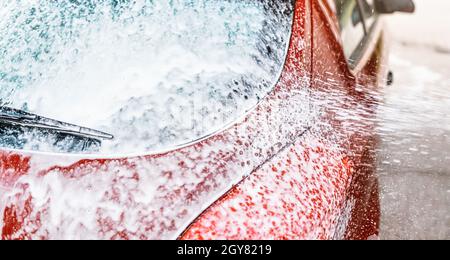 Detail auf Auto Heckscheibe mit Seifenschaum bedeckt, mehr Sprühen aus der Bürste, wenn in Autowäsche gewaschen. Stockfoto