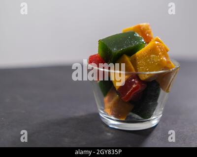 Glas mit farbenfroher mexikanischer Fruchtpaste auf schwarzer Oberfläche Stockfoto