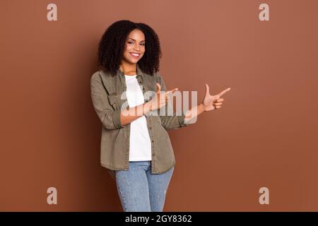 Foto von niedlichen tausendjährigen Brünette Dame Punkt leeren Raum tragen khaki Shirt isoliert auf braunen Hintergrund Stockfoto