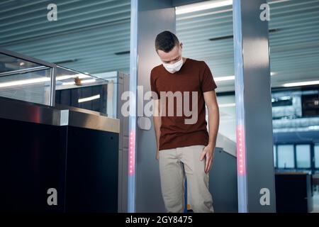 Sicherheitskontrolle am Flughafen. Passagiere, die durch das Tor des Metalldetektors fahren. Stockfoto